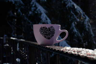 Close-up of heart shape coffee cup on railing