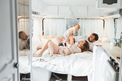 Family with baby on the bed in trailer in the morning. newborn child traveling in camper with