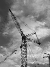 Low angle view of crane against cloudy sky