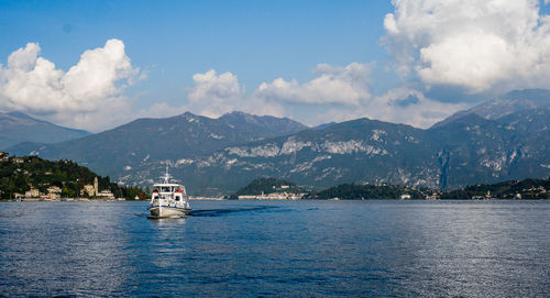 Boat on lake como by mountains against cloudy sky