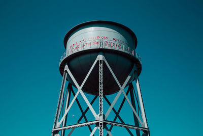 Low angle view of water tower against clear blue sky