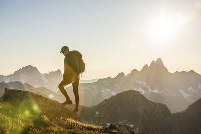 Backpacker hiking towards mountain summit on scenic mountain ridge.