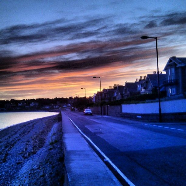 sunset, sky, cloud - sky, transportation, the way forward, road, cloud, cloudy, orange color, diminishing perspective, road marking, dramatic sky, street, street light, dusk, building exterior, built structure, weather, architecture, nature