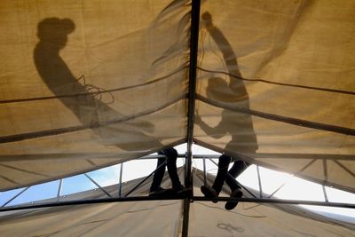 Shadow of workers on tent canvas