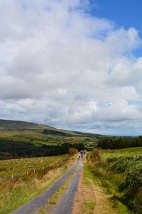 Road amidst field against sky