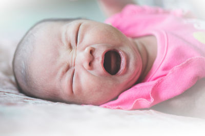 Baby girl crying while lying on bed