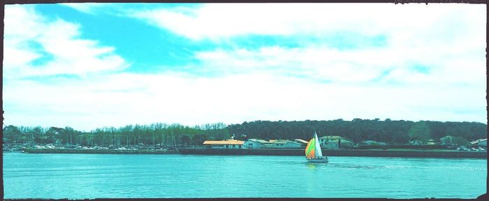 Sailboats in river against sky