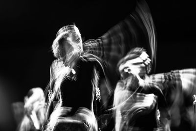 Blurred motion of dancer dancing against black background