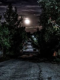 Road amidst trees against sky at night