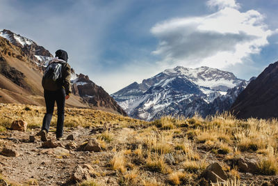 Rear view of hiker walking on mountain against sky