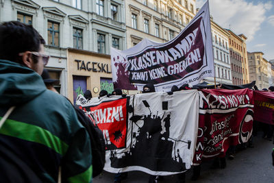 Crowd walking on street by buildings at may day