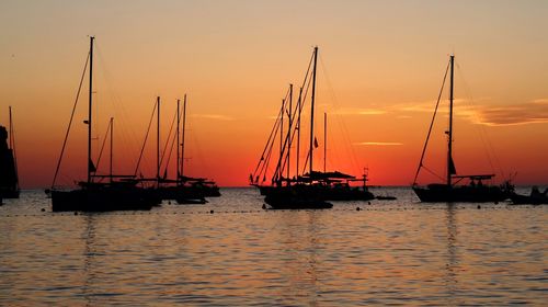 Sailboats in sea against sky during sunset