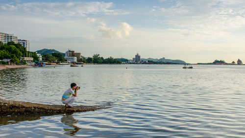 Man photographing river in city