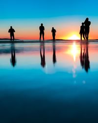 Silhouette friends enjoying in sea against sky during sunset
