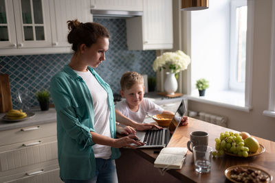 Mother working near eating son