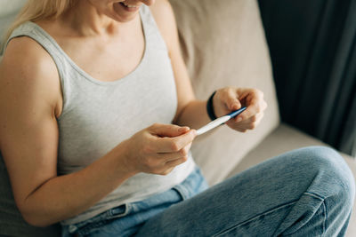 Unrecognizable woman checking pregnancy test, waiting for test result.