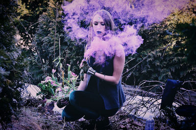 Midsection of woman sitting against trees in forest