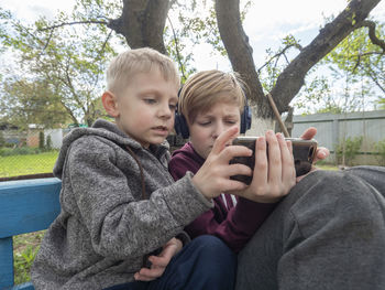 Brothers using mobile phone in back yard