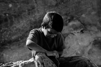 Teenage boy sitting on rock