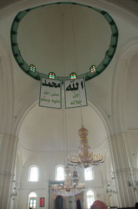 Low angle view of illuminated lighting equipment hanging on ceiling of building