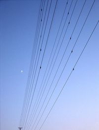 Low angle view of power lines against clear blue sky