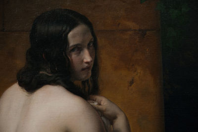 Portrait of shirtless young woman against wall