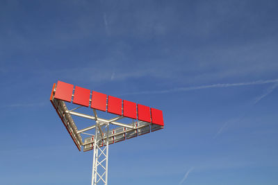 Low angle view of red sign against blue sky
