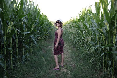 Portrait of smiling woman standing on field amidst cereal plants