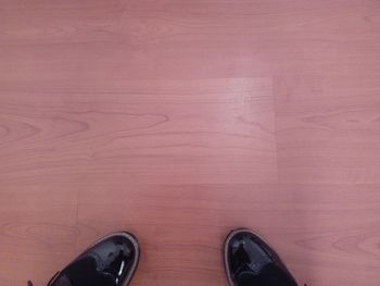 Low section of person standing on hardwood floor