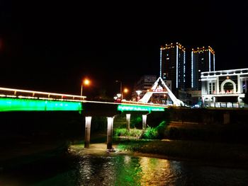 Illuminated bridge over river against sky at night