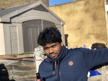 Portrait of young man standing against wall outdoors