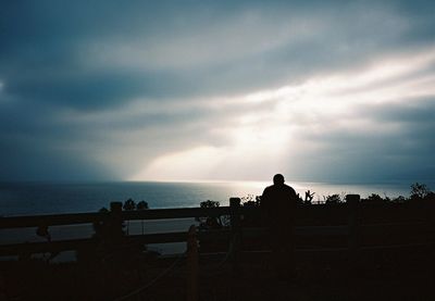 Silhouette of people looking at sea