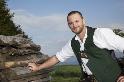 Portrait of man in traditional clothing standing by wood