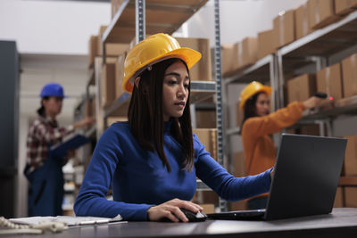 Portrait of young woman using laptop while standing in city