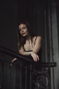 Young woman standing by railing at home