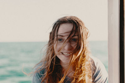 Portrait of smiling young woman against sea