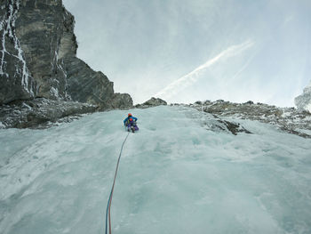 Rear view of woman climbing on frozen waterfall