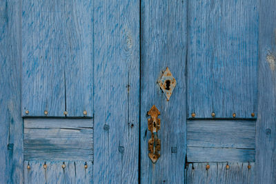 Close-up of rusty handle on old wooden door