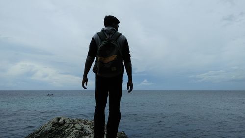 Rear view of man looking at sea against sky