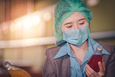 Close-up of woman wearing mask inspecting drinks in factory