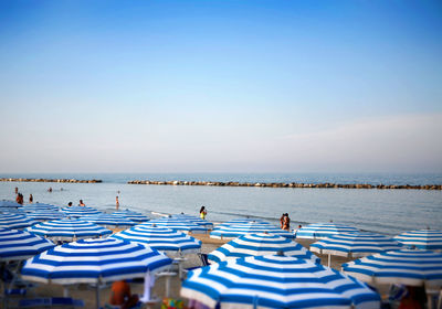 Striped blue parasols at beach against sky