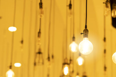 Low angle view of illuminated light bulb hanging from ceiling