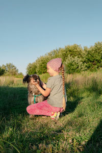 Little girl hugging playing with dog walking spending time together. child with pet in summer meadow