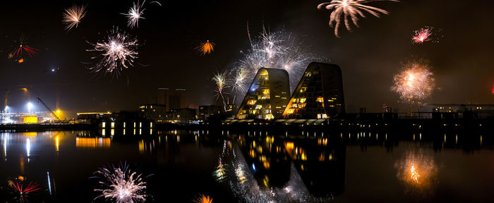 Reflection of illuminated buildings and fireworks in river at vejle