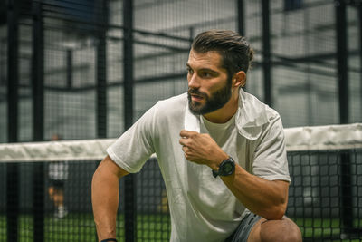 Man playing padel tennis, racket in hand wipes the sweat. young sporty boy at the end of the match. 