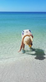 Boy on beach by sea against sky