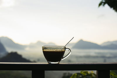 Close-up of coffee on railing against sky