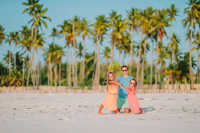 Full length of mother and daughter on palm trees on beach