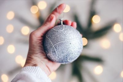 Close-up of human hand holding christmas bauble at home