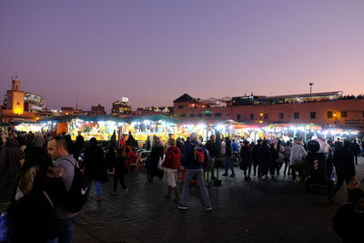 People at illuminated market against clear sky at night